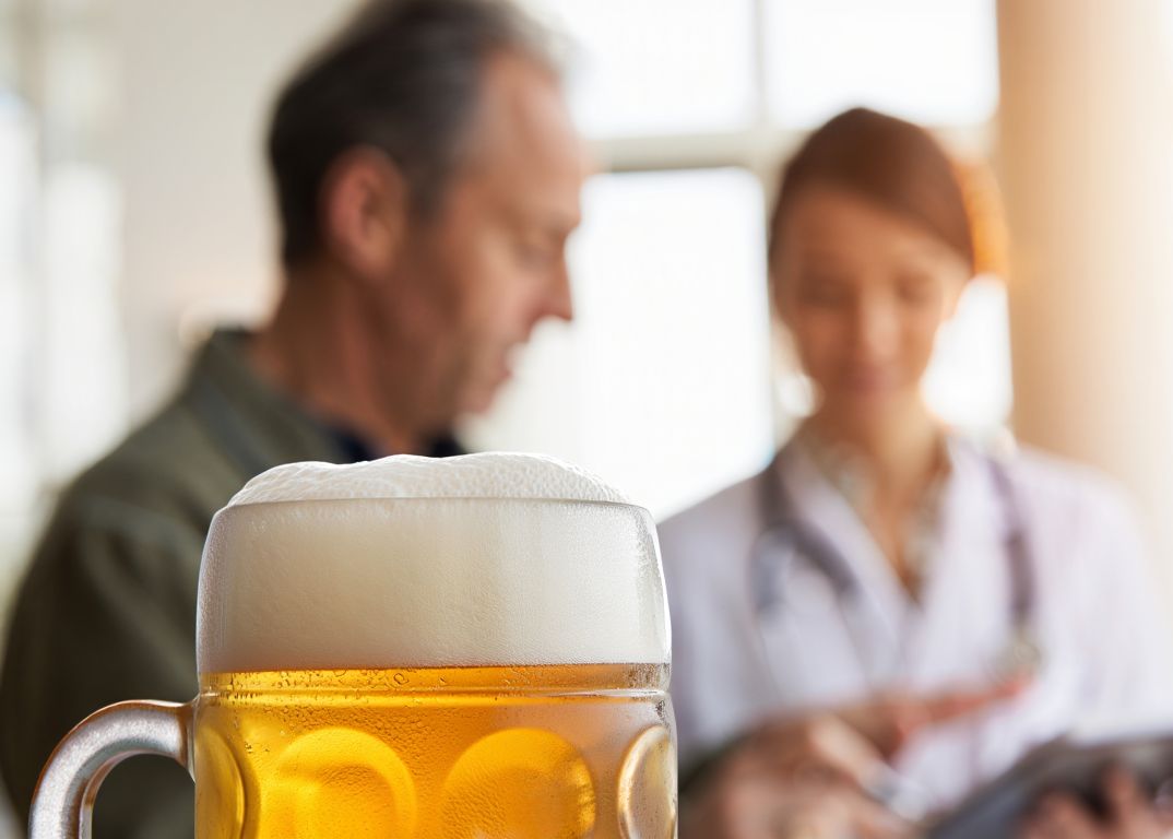 Мужчина беседует с врачом на фоне кружки пива